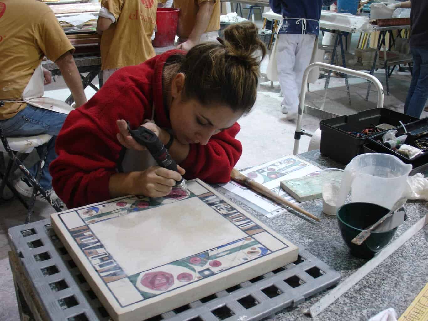 Alumna trabajando técnica de estuco mármol sobre panel decorativo en taller de El Barco