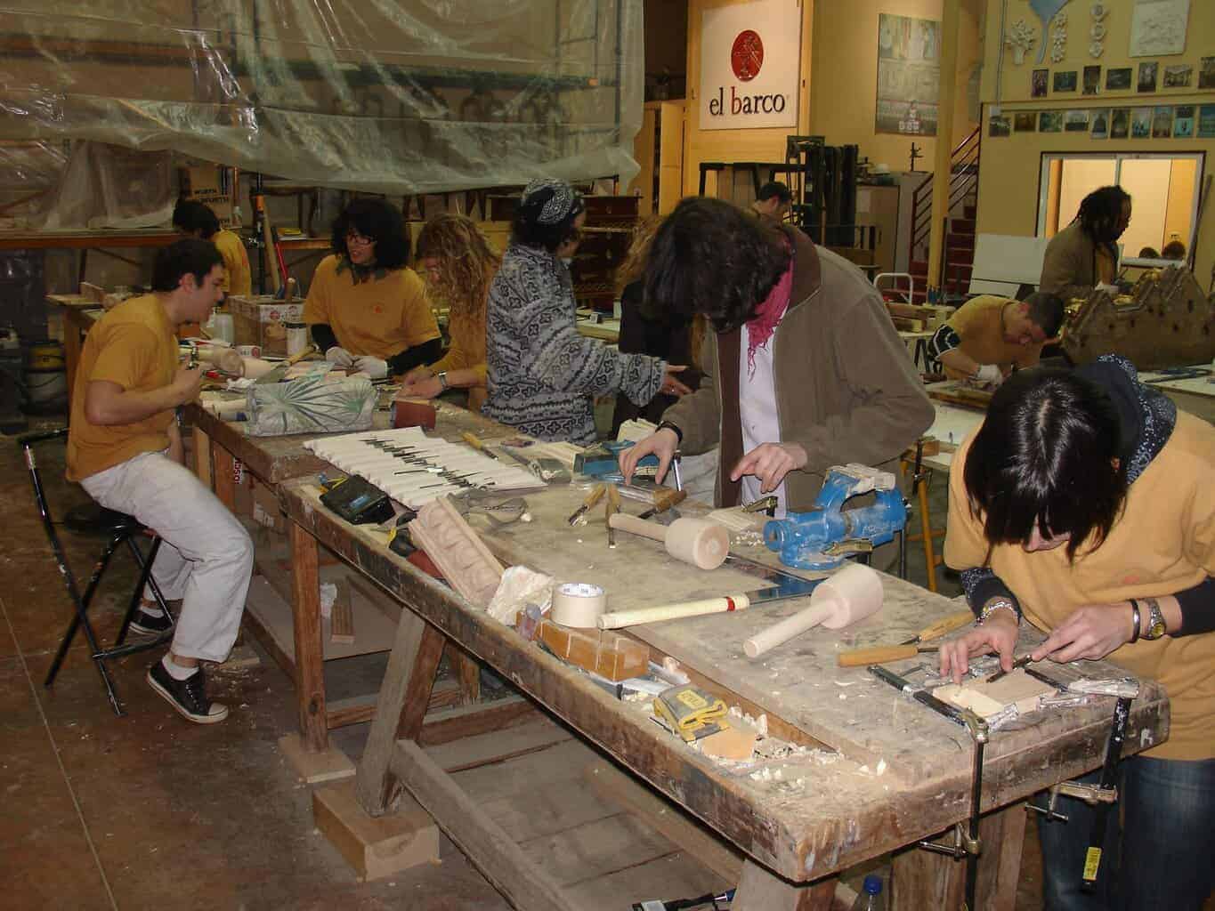 Grupo realizando prácticas coordinadas de restauración de madera en varias mesas